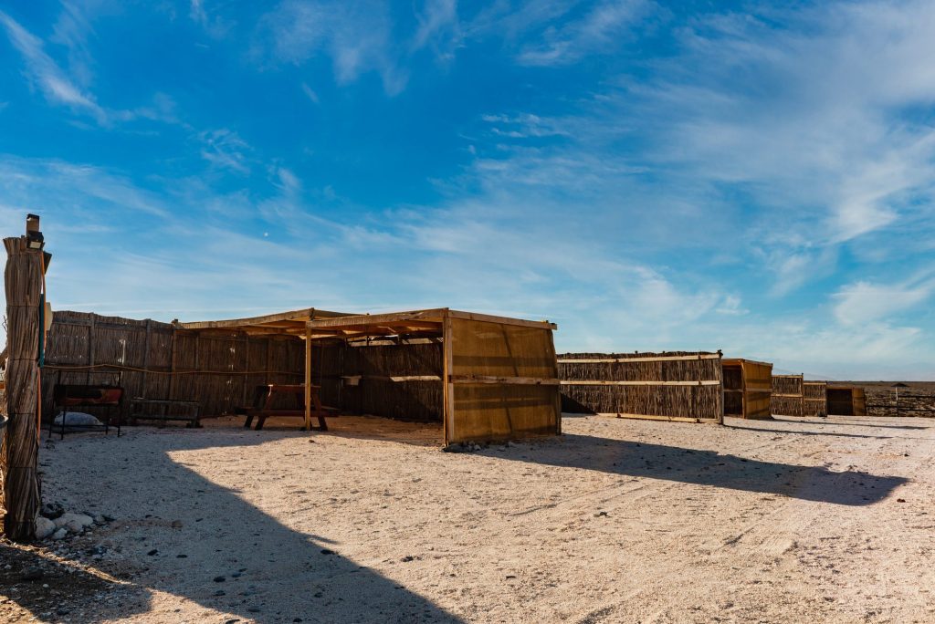 Pérgola de madera sobre la arena, junto a las cabañas