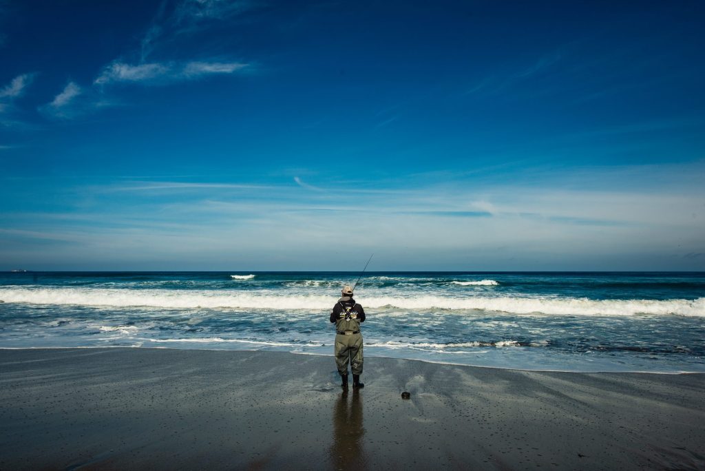 Pescador con caña en la orilla de la playa