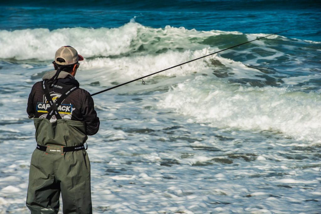 Pescador lanzando la caña desde la orilla